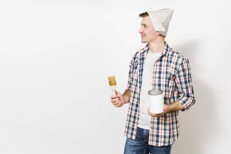 年轻的微笑英俊的男子在报纸帽子持有油漆刷和空漆锡可以与复制空间隔离在白色背景。翻新公寓房间的仪器。修复主页概念