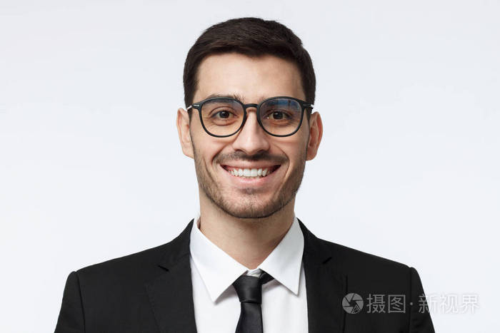 照片 年轻的欧洲白种男性在灰色背景下的室内特写与眼镜和正式的黑色