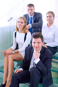 青年生意人的画像在办公室与同事在背景。青年商人画像
