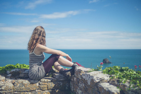 夏天，一个年轻的女人正在海边的墙上放松