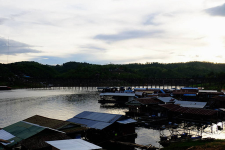 当太阳在傍晚前落下时，五彩缤纷的天空。泰国SangklaburiKhaoLaem水坝附近的河流和大坝周围社区的游客和景观。5月2