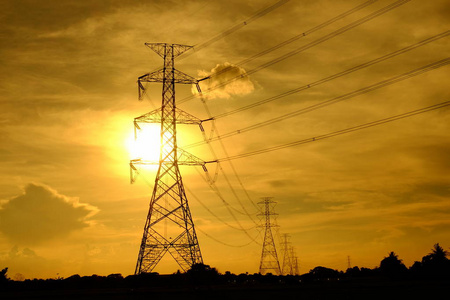 高压输电塔将电力从发电厂输送给人们。 夕阳下金色的天空