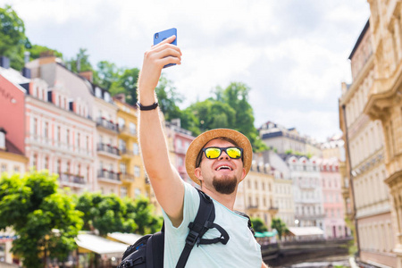 英俊的男子采取自拍手机智能手机相机在欧洲城市。假期旅游和度假概念