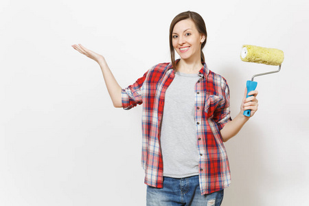 年轻的女人拿着油漆滚筒，用于墙上的绘画，把手放在白色背景上孤立的复制空间上。 翻新公寓房的仪器配件工具。 修理家庭概念