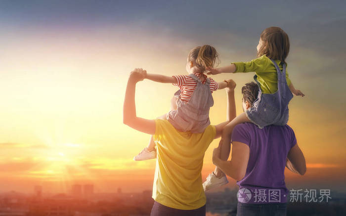 日落时的幸福家庭父亲母亲和两个女儿在大自然中玩得