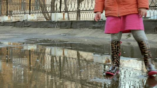 小漂亮女孩雨后跳在水坑上