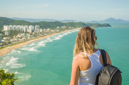 伟大的度假概念和旅行者年轻的女人带着背包看地平线海滩。