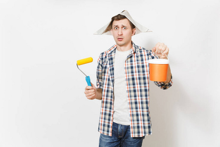 仪器室年轻关心的人戴着报纸帽子,拿着油漆滚筒,用于墙上的油漆和空漆