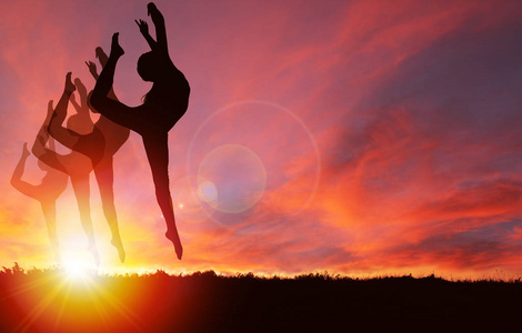 女孩跳舞和跳跃的轮廓与充满活力的金色日出或日落背景和复制空间.