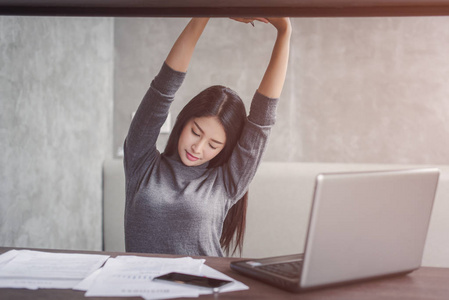 穿着西装,坐在笔记本电脑前的办公桌前,享受着工作完成后看着屏幕的