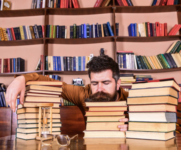 男人在睡觉的时候躺在成堆的书里, 在书房里睡觉, 在书架上看书。Overstudied 概念。有胡子的老师或学生在书本上睡着了