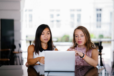一个由两名同事一名中国亚洲妇女和一名高加索白人妇女组成的多元化团队的肖像，在当天的笔记本电脑上查看DCF现金流模型。