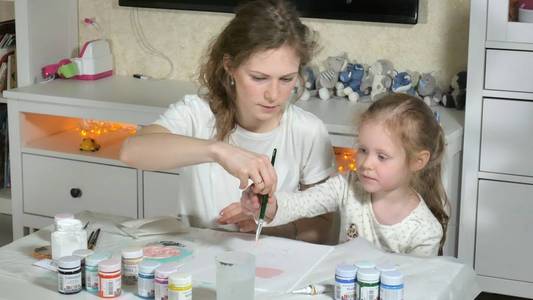 母亲和孩子用彩色手指作画。儿童游戏对幼儿发育的影响