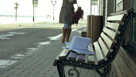 年轻, 美丽, 可爱的女人坐在公园的长凳上, 在她的笔记本手。她穿着一件大衣。她做笔记, 看起来很浪漫