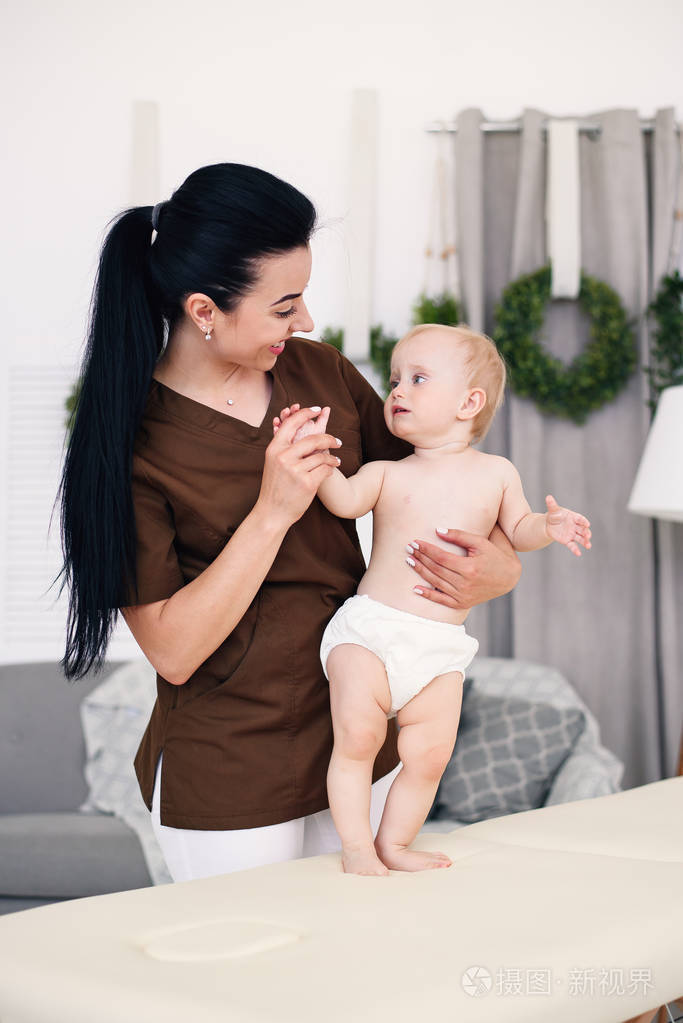 专业女按摩师给小宝宝做按摩..儿童按摩沙发在一个现代舒适的房间。