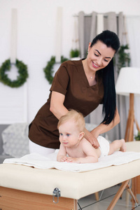 专业女按摩师给小宝宝做按摩..儿童按摩沙发在一个现代舒适的房间。