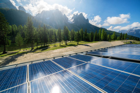 太阳能电池面板在乡村景观与阳光明媚的天空和山脉背景。太阳能是世界能源可持续性的创新。可持续资源。