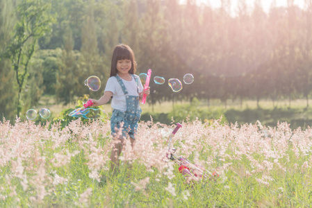 无忧无虑的孩子在绿色的夏季草地上奔跑和跳跃,捕捉肥皂泡.