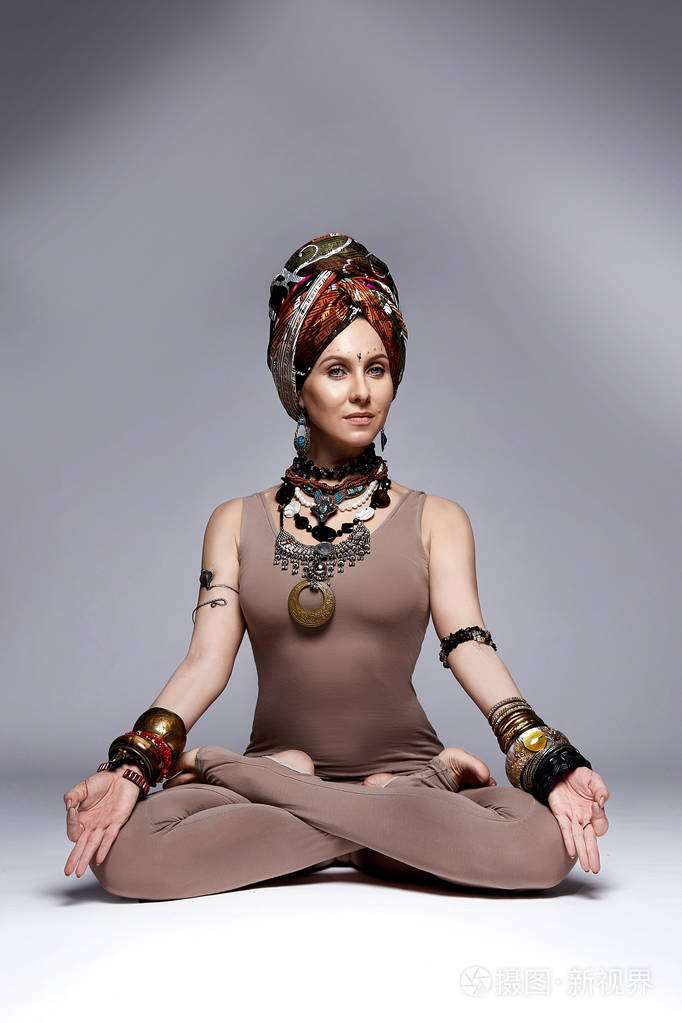 美丽性感年轻女子金发碧眼穿西装配饰珠宝手镯项链帽子印度式瑜伽姿势