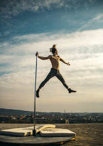 钢管塔性感的男人在天空背景上飞翔. 钢管舞运动.