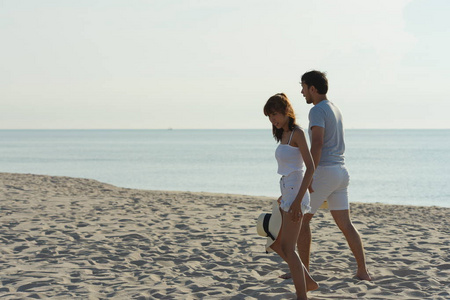 年轻夫妇在日出的清晨在海滩上锻炼和跳跃。 美丽的黄色天空