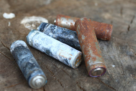 涂有腐蚀的废电池. 不同的形状和大小. 躺在木桩的边缘.