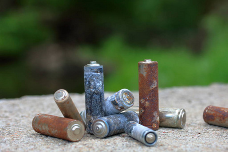 不同的电池涂有腐蚀的废电池. 不同的形状和大小. 躺在混凝土表面.