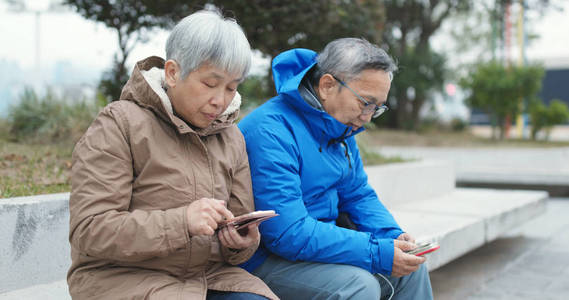 一对老夫妇在街上一起用手机