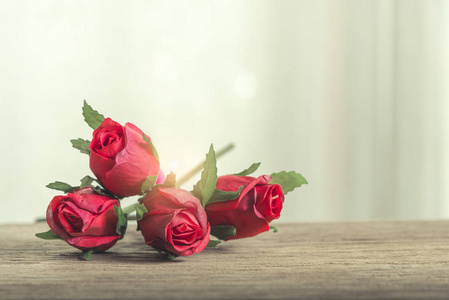 情人节爱情和婚礼背景概念。 木制桌子上的红色玫瑰，有窗灯背景。 图片用于添加文本消息。 设计艺术作品的背景。