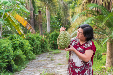 持有榴莲的亚洲女农是泰国的水果之王，亚洲的水果有穗壳，甜可以在泰国街头购买，在农业农场的水果市场购买。
