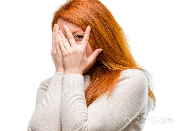 美丽的年轻红发女子微笑着害羞地看着用手指捂住脸双手