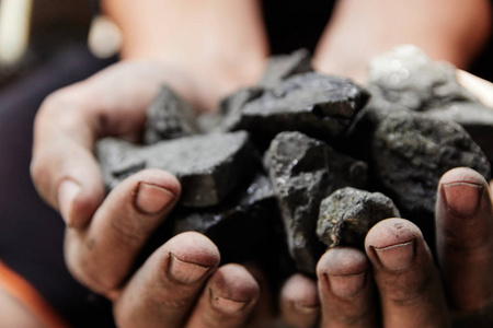 煤矿工人手中的煤背景。 采煤或能源环境保护。 工业煤。 火山岩。