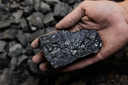 煤矿工人手中的煤背景。 采煤或能源环境保护。 工业煤。 火山岩。