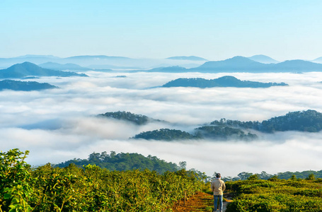 伫立在高山风景秀丽的乡村故乡上的年轻人，清晨的山谷里，雾气笼罩着群山，隐约可见大片起伏的风景名胜区，是越南的故乡