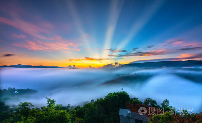 清晨高原上的黎明五彩缤纷的天空太阳从地平线升起照射到笼罩着雾气的