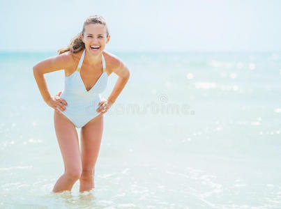 站在海里的一位身穿泳衣的微笑的年轻女子