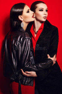 两位美丽时尚的黑发白种年轻女性模特，身穿黑色夹克，妆容鲜艳，