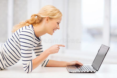 微笑的学生女孩用手指着笔记本电脑