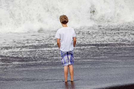 小男孩在黑色火山海滩玩得很开心