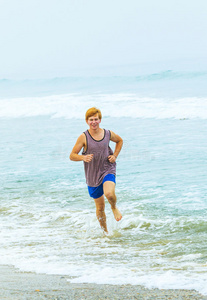 在空荡荡的海滩上慢跑的年轻男孩