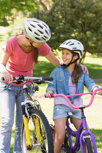 带着女儿骑自行车的微笑的女人