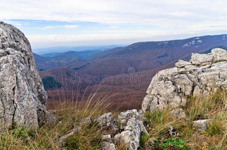 在阳光明媚的秋日，几片云彩映衬下，莫洛耶山脉的风景山峰和岩石