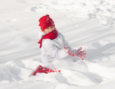 戴红帽子的女孩在雪地里玩耍