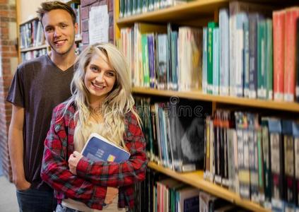 站在图书馆书架旁的学生图片