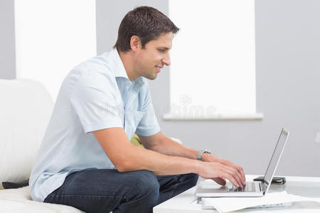 家中使用笔记本电脑的微笑男士侧视图