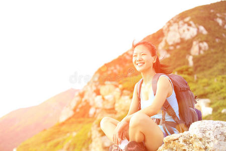 女徒步旅行者坐在海边的山上