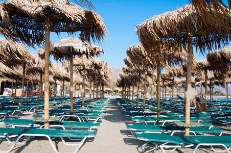希腊克里特岛埃拉弗尼斯海滩上的雨伞和日光浴床