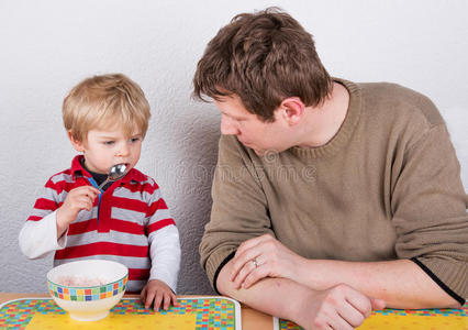年轻的父亲和小儿子在家里的厨房吃饭。