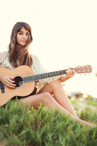 美丽的年轻女子在沙滩上弹吉他