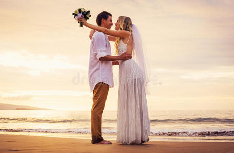 日落时海滩上的新郎新娘